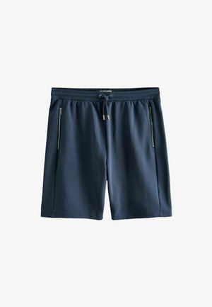 Tengerészkék térdig érő rövidnadrág gumis derékrésszel, húzózsinórral és két függőleges cipzáras oldalzsebbel, fehér háttéren laposan elhelyezve.