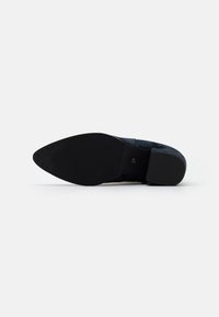 Scarpa in suede nera con punta affusolata, suola in gomma testurizzata e tacco liscio accentuato. Presenta un design piatto e strutturato. Taglia 37.