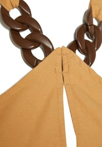 Tan-färgad tyg med andningsbar textur har en splittek_detail som är ihopkopplad med en mörkbrun, glänsande plastkedjeaccessoar vid kragen.