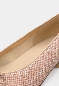 Μπαλαρίνα σε ροζ υφαντό υλικό με λείο, μπεζ εσωτερικό. Διαθέτει στρογγυλεμένη μύτη και ελάχιστη διακοσμητική λεπτομέρεια στη μπροστινή πλευρά.