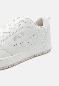 Sneaker bianche in pelle con dettagli perforati, punta rotonda, suola in gomma testurizzata e branding discreto sul lato.