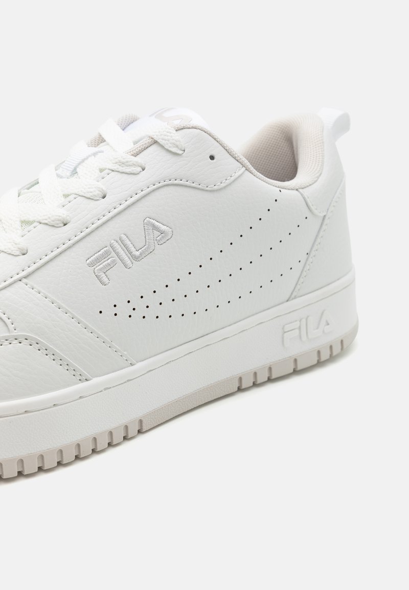 Baskets en cuir blanc avec des détails perforés, bout rond, semelle en caoutchouc texturé et branding discret sur le côté latéral.