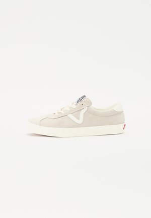 Licht beige lage sneaker met witte zool, wit zijaccent, crèmekleurige veters en een gebrande zwart-witte tonglabel.