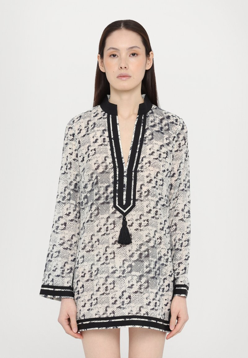 Rochie albă transparentă cu un model abstract negru, mâneci lungi, guler, detalii contrastante negre și un ciucure la decolteu.