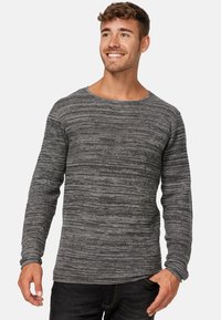 Pulover gri cu mânecă lungă, având un model texturat în dungi și un decolteu rotund. Fabricat dintr-un material moale, asociat cu blugi negri.