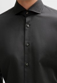Schwarzes Hemd mit Knopfleiste, strukturiertem Kragen, tonalen Knöpfen und einem strukturierten Stoff mit einem dezenten diagonalen Muster.