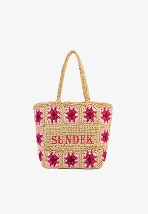 Borsa a tracolla beige all'uncinetto con motivi quadrati floreali rossi e rosa e testo rosso "SUNDEK" sul davanti, dotata di due manici.