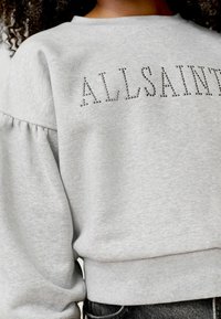 Sivi dukserica s okruglim izrezom i napuhanim rukavima, ukrašena logotipom od cirkona koji glasi "ALLSAINTS". Mekana tekstura tkanine.