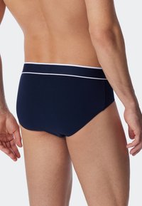 Slip blu navy in cotone con elastico bianco in vita. Il design è aderente, con una texture liscia e uno stile minimalista.