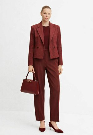 Bordový tweedový blejzer s výstrihom do límca, zladené nohavice a lodičky so špicatou špičkou, doplnené o štruktúrovanú kabelku so zlatou kovovou výbavou.