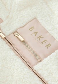 Interno in pile color crema con una consistenza morbida, dotato di una tasca con cerniera dorata e un'etichetta con "BAKER by TED BAKER" in lettering dorato.