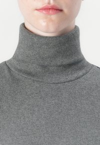 Grijze geribbelde coltrui, met een hoge kraag en een zachte textuur, ontworpen voor een aansluitende silhoutte rond de nek en schouders.