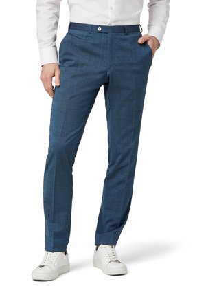 Herren blaue Hose aus strukturiertem Stoff, mit geradem Schnitt, Seitentaschen und einer vorderen Knopfleiste, kombiniert mit weißen Turnschuhen.