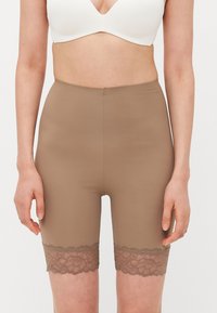 Bruine elastische shorts met kant aan de zoom, met een gladde textuur en een hoog tailleontwerp, gecombineerd met een witte bh-top.