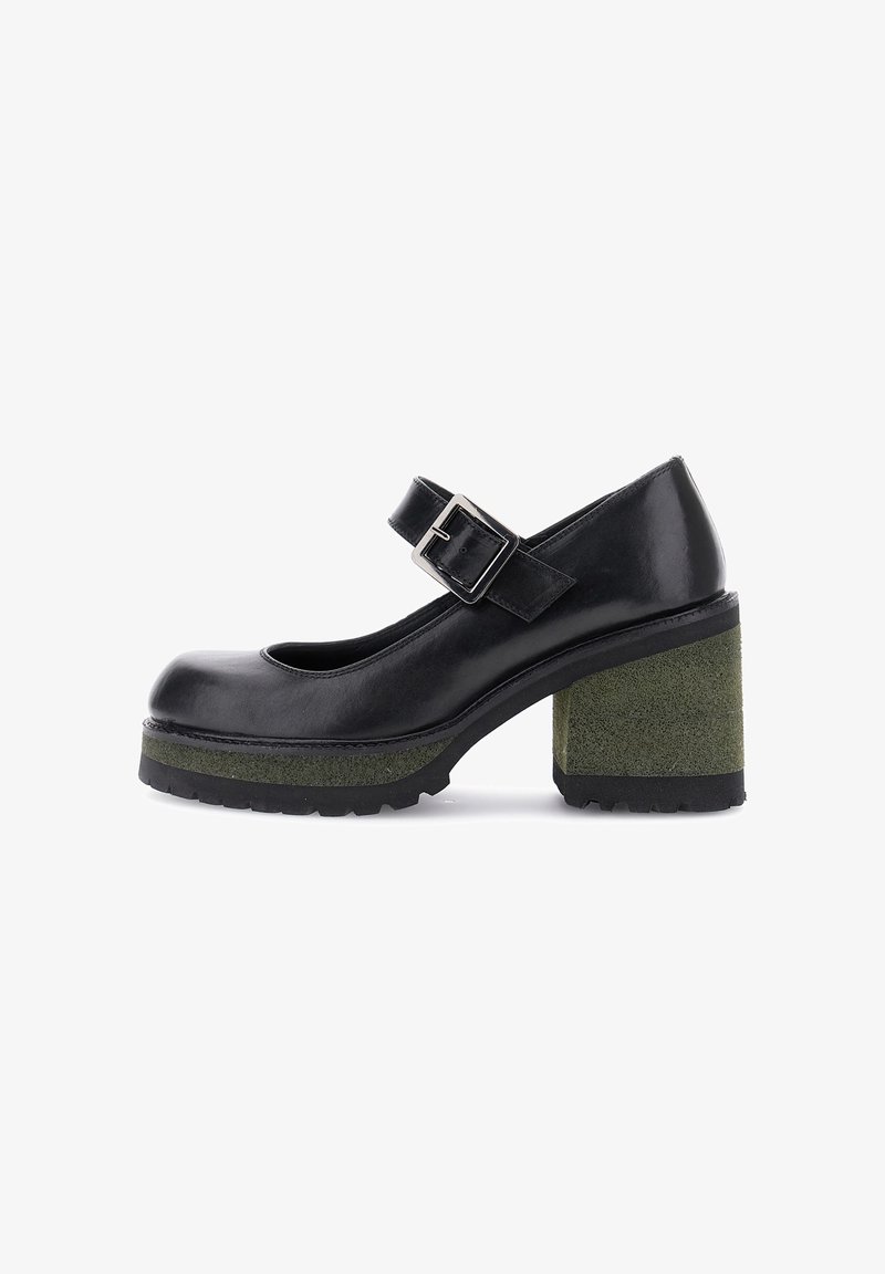 Zapato negro tipo Mary Jane con grueso tacón de plataforma verde y correa de hebilla plateada, vista lateral sobre fondo blanco.