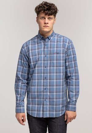Niebieska koszula w kratkę, z długimi rękawami, kołnierzykiem zapinanym na guziki i małą kieszonką na piersi. Wzór zawiera czarne i białe linie rozmieszczone w kratce.