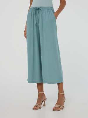 Pantaloni a gamba larga color turchese chiaro con vita elastica e cordino, dotati di tasche laterali e tessuto morbido e fluido.