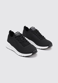 Zapatillas negras de tela de punto con suela blanca, con cordones negros planos, puntera redondeada y etiqueta "ECOALF" en la lengüeta.