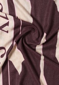 Coperta lavorata a maglia con un motivo a spirale, caratterizzata da strisce di un profondo bordeaux, beige chiaro e rosa. Texture morbida e spessore consistente.