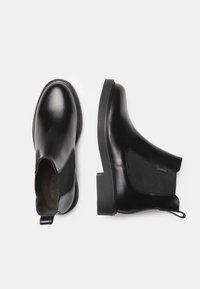 Black leather ankle boots with elastic side panels, rounded toe, and pull tab at the heel, featuring a textured rubber sole.