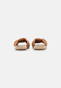 Akrilni slip-on �čevlji iz rjave tkanine z vozlovnim vzorcem, odprt hrbet in pleteno jute podplat. Notranji podplat je gladek, kar zagotavlja sproščen stil.