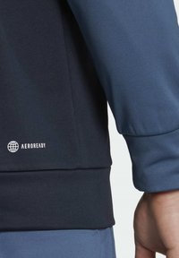 Dark navy and light blue athletic top, featuring a smooth texture, fitted design, and white "AEROREADY" logo near the hem.