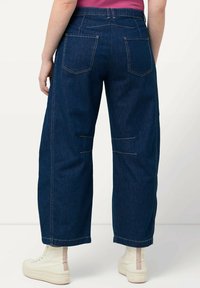 Dunkelblaue weite Jeans mit hoher Taille, elastischem Bund und Gesäßtaschen, die über Stickdetails und eine glatte Denim-Oberfläche verfügt.