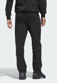 Zwarte joggingsbroek met een loose fit, elastische tailleband en ribbels aan de enkels. Gecombineerd met zwarte sportschoenen en een geweven stofdesign.