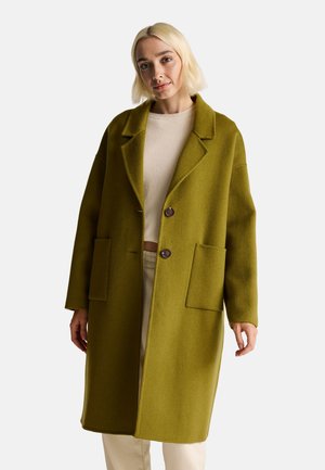 Abrigo de lana verde oliva con cuello con muescas, dos bolsillos frontales y dos botones redondos. El diseño es de corte holgado con una textura suave.