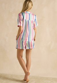 Īsais piedurknes pidžamu komplekts daudzkrāsainās vertikālās svītrās, ar apkakles kreklu un atbilstošām šortiem ar kabatām. Gluda, viegla auduma.