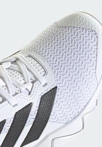 Witte sportschoen met een bovenwerk van mesh, zwarte accenten, gestructureerde overlays en een gewatteerd zoolontwerp met opvallende veters.