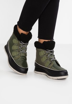 Groene waterdichte laarzen met zwarte rubberen zolen, een zachte zwarte kraag en grijze veters. Ontworpen voor warmte met geaccentueerd textuurmateriaal.