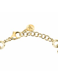 Bracciale a catena placcato oro con anelli circolari intrecciati, chiusura a granchio e un'etichetta rotonda con design di foglia.