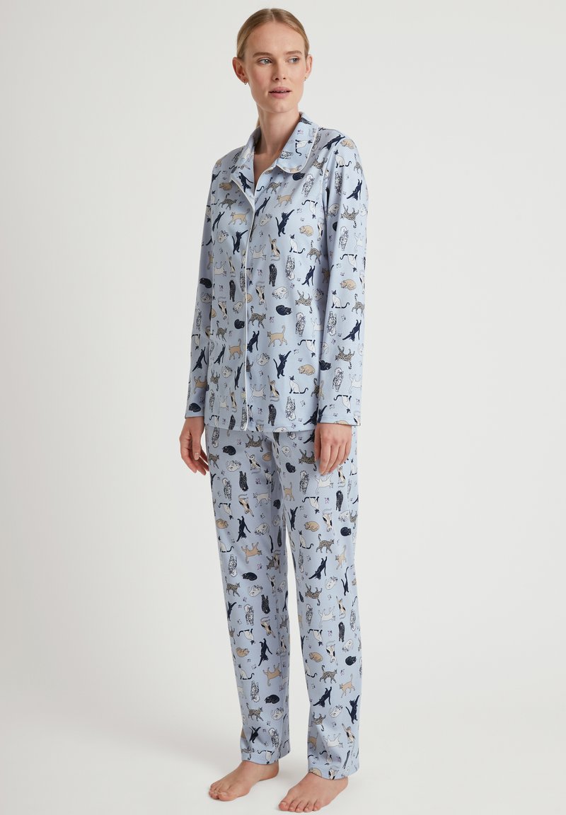 Blaue Baumwoll-Pyjama-Set mit einem allover Tiermotiv. Das Oberteil hat einen Kragen und eine Knopfverschluss; die Hose hat eine lässige Passform.
