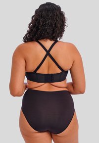 Ensemble de sous-vêtements noir comprenant un soutien-gorge avec fermeture à l'arrière et des bretelles croisées ainsi que des panties taille haute. Tissu lisse avec un minimum de détails.