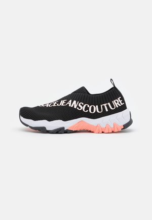 Czarny wsuwany sneaker z białą i różową podeszwą, dzianinową cholewką oraz napisem "SPACEJEANS COUTURE" po boku.