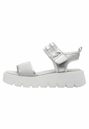 Sandale argentée avec une tige en mesh, une large sangle, une bande élastique et une semelle extérieure épaisse en caoutchouc blanc avec un motif strié.