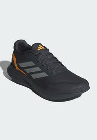 Schwarzer Sportschuh mit orangefarbenen Akzenten und grauen Details. Verfügt über ein strukturiertes Obermaterial, Schnürsenkel und eine gepolsterte Sohle, die mit "CLOUDFOAM" beschriftet ist.