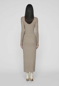 Ribbed knit dress in beige, long-sleeved, form-fitting silhouette, knee-length. Paired with glossy beige ankle boots.