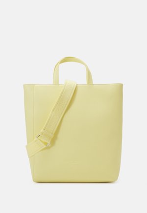 Miękka żółta torba na ramię z uchwytami u góry i regulowanym paskiem na ramię na białym tle.