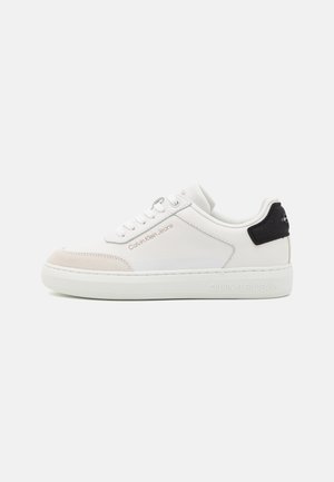 Zapatilla blanca Calvin Klein Jeans de corte bajo con diseño de cordones, detalle en beige en la punta y lengüeta negra en el talón, mostrada de perfil.