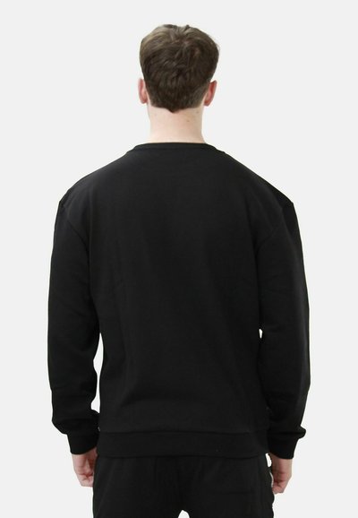 Felpa nera con collo rotondo e maniche lunghe, caratterizzata da una texture liscia, polsini a coste e orlo dritto. Nessun motivo visibile.