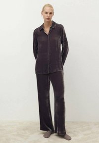 Lila Samt-Schlafanzug-Set mit einer knöpfbaren Oberseite mit Kragen und passenden lockeren Hosen; weiche Textur und subtiler Glanz.