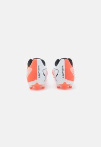 White and neon orange soccer cleats with a distinctive heel design, textured material, and a black accent on the collar.