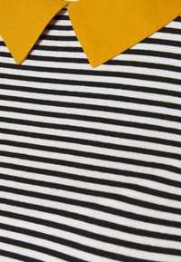 Svart och vit randig tyg med en gul krage. Texturen verkar mjuk och slät, medan kragen har en något upphöjd design.