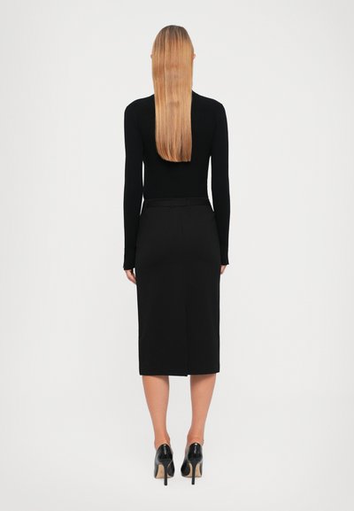 Black ribbed long-sleeve top paired with a black mid-length skirt. Textured fabric with a fitted design and high-heeled black shoes.