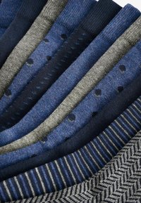 Collection of men's socks in navy, gray, and blue hues. Features various patterns including stripes and polka dots, made from textured fabric.