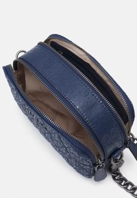 Marinenblå crossbody taske lavet af struktureret læder med quiltet mønster, der har to lynlåsrum og en kædestrop.