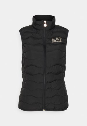 Černá prošívaná bezrukávová vesta s vysokým límcem, se zapínáním na zip vpředu a zlatým logem "EA7 Emporio Armani" na levé straně.