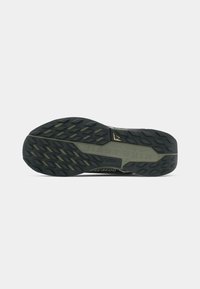 Melnās un oliņu krāsas Nike taku skriešanas apavu zole ar tekstru grip un "NIKE TRAIL" zīmolu.
